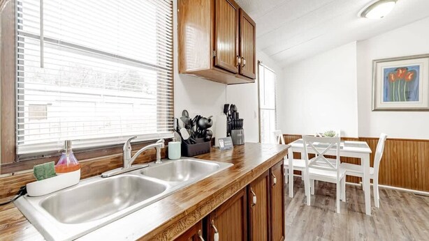 A kitchen with wooden cabinets, a double sink, and a dining area with white chairs. - 15mins to Downtown- Adorable on Taylor, Both Units (West Columbia)