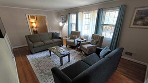 A living room with a sofa, armchairs, a coffee table, and a rug.