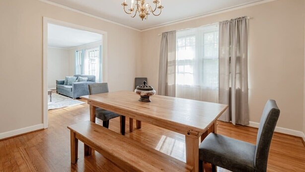 A dining area with a wooden table, benches, and a chandelier.