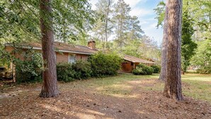 A rustic house surrounded by tall trees and dense foliage.