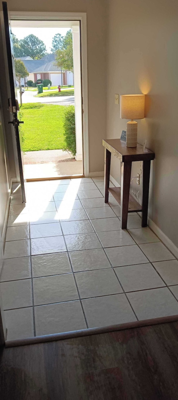 Enter a serene space with a clean, minimalist design, featuring a glass door leading to a bright outdoor area.