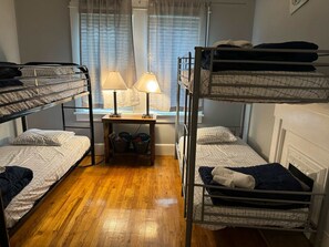 Cozy dormitory room with bunk beds, a desk, and a fireplace.