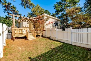 Enjoy a serene retreat in a beautifully landscaped yard with a shaded pergola, white picket fence, and a charming porch.