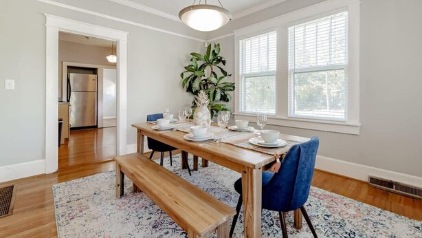 A dining area with a wooden table set for four, a bench, and a potted plant.