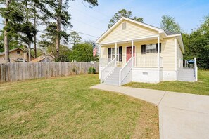 A charming single-story house with a front porch and a well-manicured lawn.