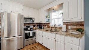 A modern kitchen with white cabinetry, stainless steel appliances, and a granite countertop. - Close to USC & Midtown-Downtown - Newly Renovated! (Columbia)