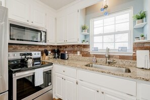Enjoy cooking in this well-equipped kitchen with a granite countertop, stainless steel appliances, and a window for natural ventilation.