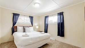 Habitación de hotel con una cama grande, dos mesitas de noche y un ventanal con cortinas.
