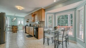 Una cocina amplia con una isla central, armarios de madera y un comedor con mesa y sillas de vidrio.