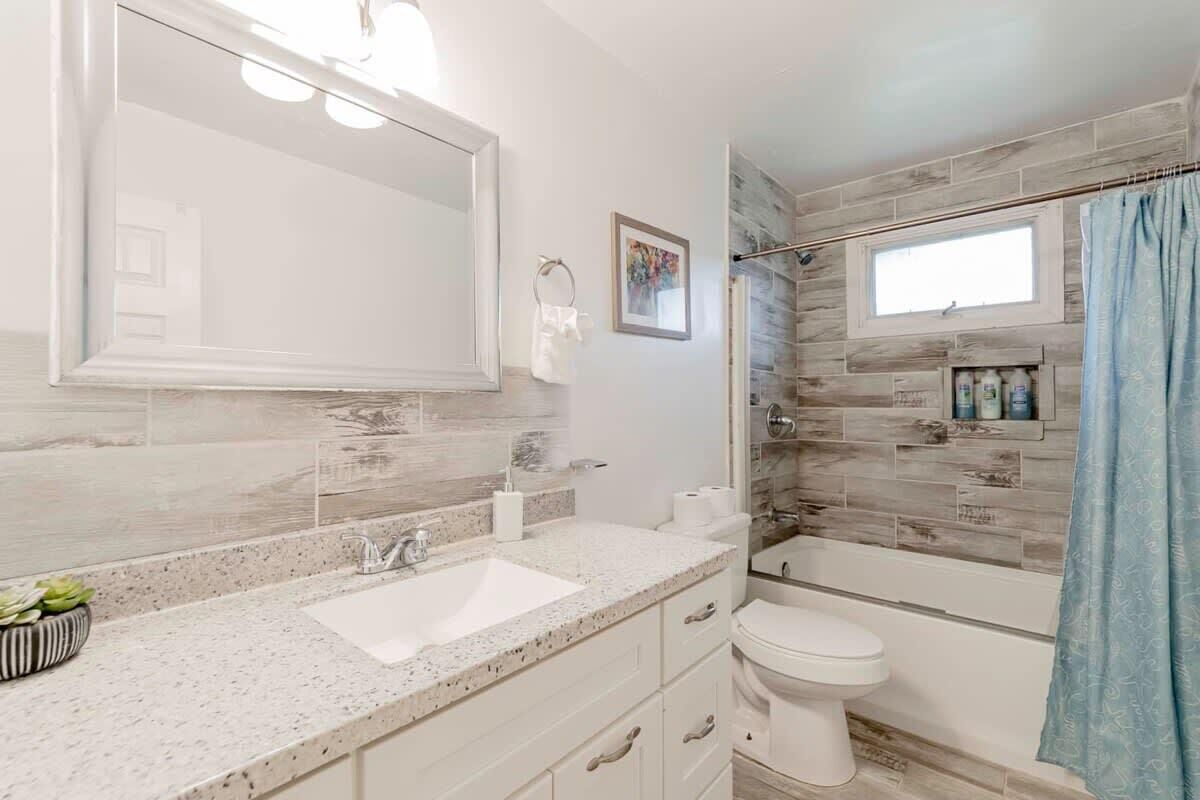 A bathroom with a white sink, a mirror, a toilet, and a shower area.