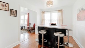 Een moderne keuken met een centraal eiland, barstoelen en een kroonluchter.