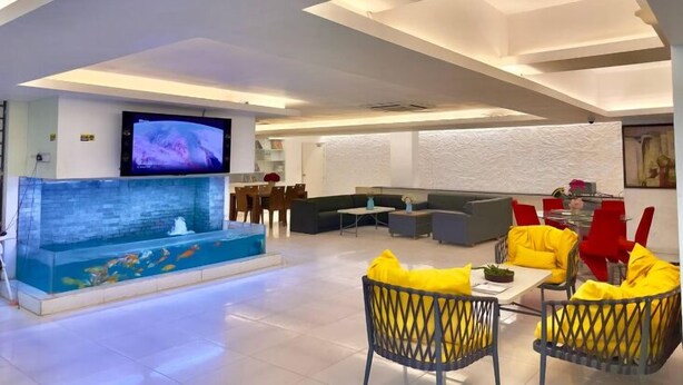 A modern living room with a flat-screen TV, a fish tank, and yellow chairs.