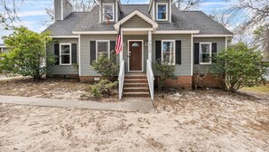 A two-story house with a front porch, a chimney, and a flag. - Large Private Yard, Near USC! - The Garnet Goliath (Columbia)