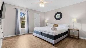A bedroom with a bed, ceiling fan, two bedside lamps, a TV, and a window with curtains. - Large Private Yard, Near USC! - The Garnet Goliath (Columbia)