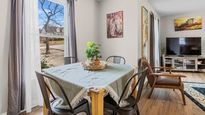 A dining area with a table set for four, a television, and artwork on the walls. - Large Private Yard, Near USC! - The Garnet Goliath (Columbia)