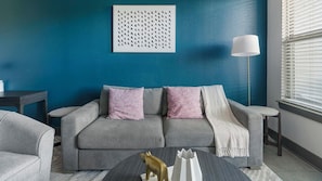 Una sala de estar moderna con una pared azul de acento, un sofá gris y una figurita decorativa de animal sobre una mesa de centro.