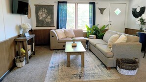A living room with a sofa, a coffee table, a TV, and a wall-mounted bull head decoration. - Mins to Downtown & Working Desk - Gamecock Roost (West Columbia)