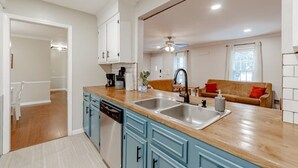 A modern kitchen with a wooden countertop, two sinks, and blue cabinets. - Mins to Lake Murray & Downtown - The Settle-Inn (Irmo)