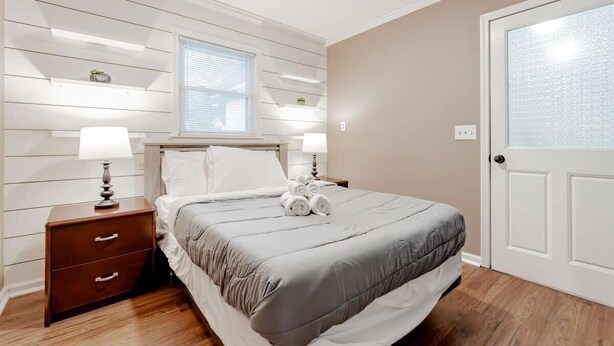 A bedroom with a bed, nightstands, a window, and a door. - Mins to Lake Murray & Downtown - The Settle-Inn (Irmo)