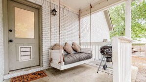 A porch with a swing bed, a grill, and a door with a window. - Mins to Lake Murray & Downtown - The Settle-Inn (Irmo)