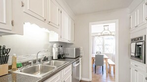Une cuisine moderne avec des meubles blancs, des appareils en acier inoxydable et un plan de travail en granit.