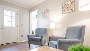 Un salon avec deux fauteuils gris, une table basse en bois et un lampadaire.