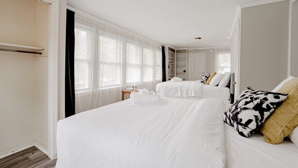 A hotel room with two beds, a wardrobe, and a large window with sheer curtains.