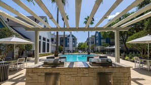 An outdoor pool area with a stone bar, lounge chairs, and umbrellas.