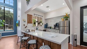 A modern kitchen with a large island, bar stools, and a view of the outdoors.