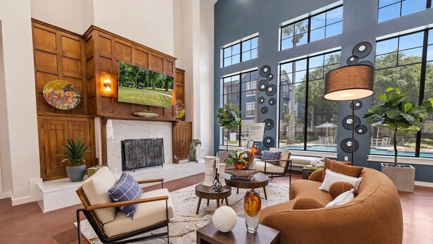 A spacious living room with a fireplace, comfortable seating, and large windows offering a view of the outdoors.