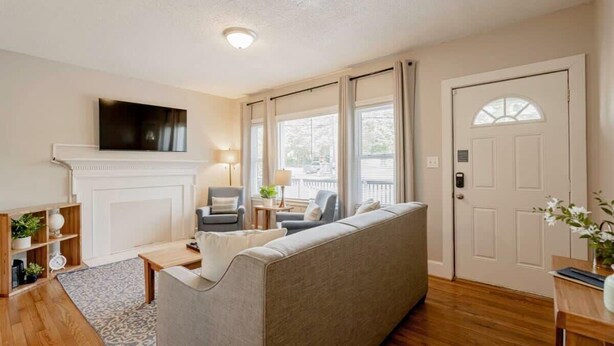 A living room with a sofa, a television, a fireplace, and a door with a window. - Mins to USC, Hospital, Zoo! Columbia Duet-Unit A (West Columbia)