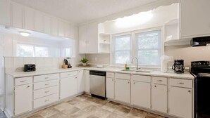A modern kitchen with white cabinetry, a dishwasher, a stove, and a window with blinds. - Mins to USC, Hospital, Zoo! Columbia Duet-Unit A (West Columbia)