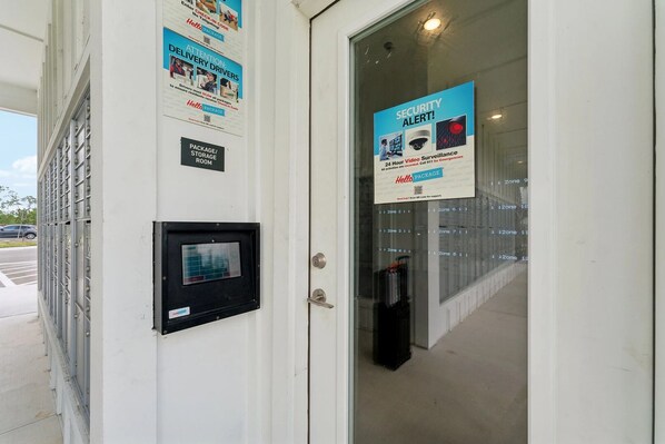 A security alert sign, a package storage room sign, and a door with a keypad lock.