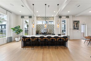 A modern kitchen with a central island, pendant lighting, and a view of the outside.