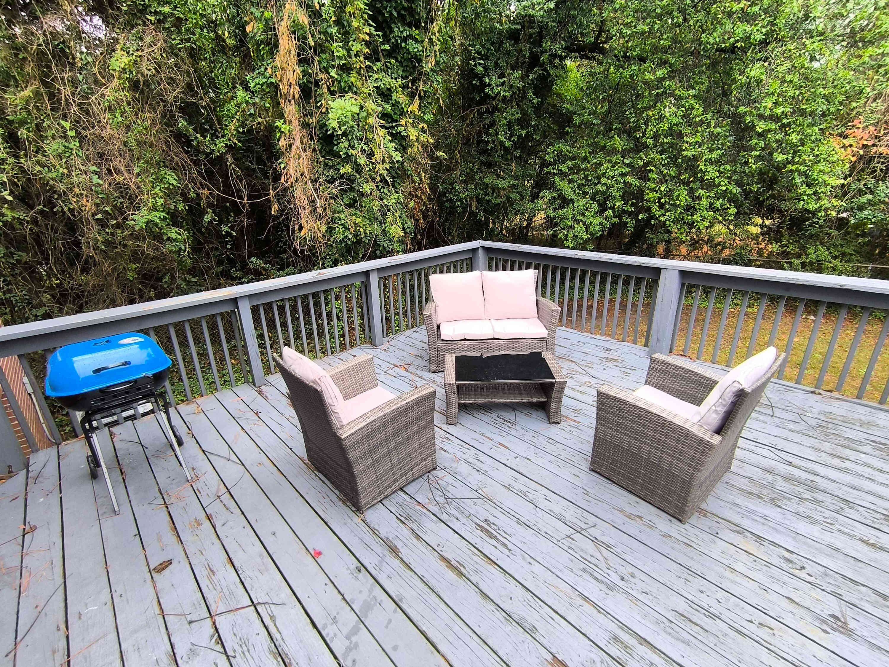 Une terrasse en bois avec des meubles en osier et un barbecue.