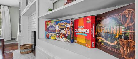 A shelf with board games including 'Family Feud', 'Charades', and 'Tama'.