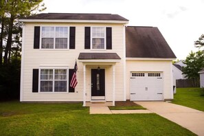 Stately two-story home with a central entrance, garage, and well-manicured lawn.