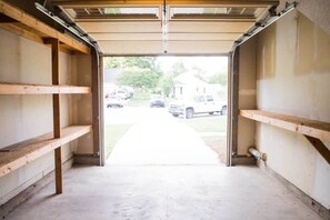 Garage with storage shelving and access to a residential driveway.