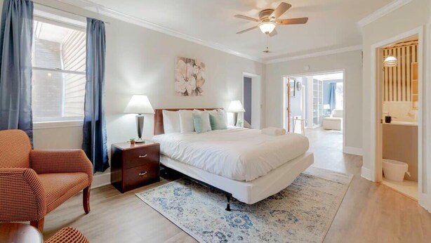 A bedroom with a bed, nightstands, a chair, a ceiling fan, and a view to the outside. - Near Downtown & On the Water! Sweet Retreat! (Columbia)