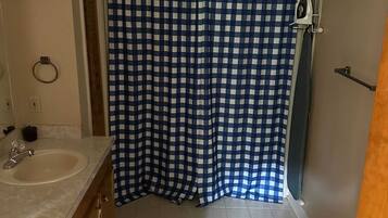A bathroom with a checkered shower curtain, a sink, and a mirror.