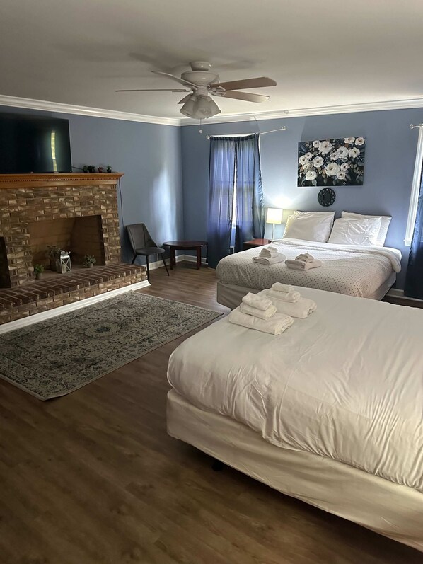 A hotel room with a fireplace, two beds, a ceiling fan, a TV, and a painting on the wall. - Near Downtown & On the Water! Sweet Retreat! (Columbia)
