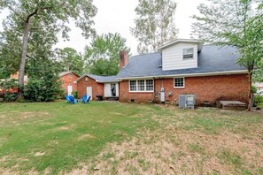 Situated in a serene yard, this home features a brick exterior, a dark roof, and a white trim.