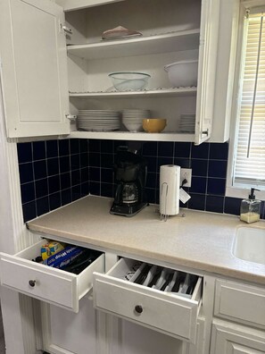 Kitchen area with white cabinetry, countertop, and dark blue tile backsplash.