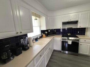Kitchen features a stainless steel stove, microwave, and sink, with a window above.
