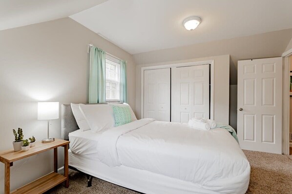 Cozy retreat with a large bed, bedside table, and window with curtains.