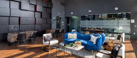 A modern living room with a blue sofa, white armchairs, and a wooden coffee table.