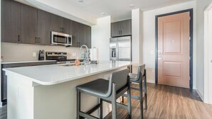 A modern kitchen with a central island, stainless steel appliances, and a wooden floor.
