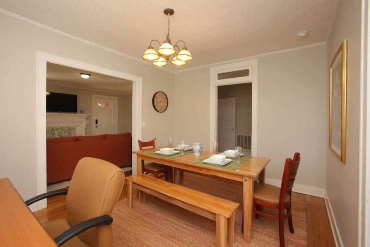 Un coin repas avec une table en bois dressée pour quatre personnes, un banc et deux chaises.