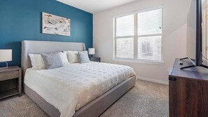 A bedroom with a bed, nightstands, a window with blinds, and a painting on the wall.