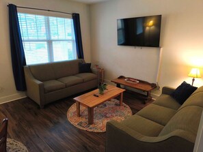 Relax in this inviting living room with a sofa, coffee table, and TV, surrounded by a large window and a patterned rug.